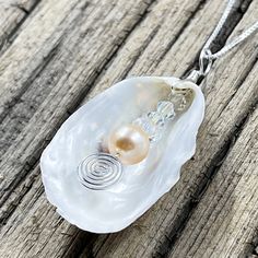 This beautiful pendant is made from a natural white oyster shell found on the beaches in the Cape May area. A spectacular metallic fresh water pearl is nestled inside the oyster shell showing off the treasure inside. The shell was then wire wrapped with sterling silver wire. The pendant measures 2 inches in length from the top of the bail and 1 inches wide. The pendant is on a 16" sterling silver box chain but other lengths are available in the below options. Seashell Jewelry, Rock Jewelry, Wire Wrapping Stones, Cape May, Fresh Water Pearl, Shell Art, Silver Box, Shell Jewelry, Oyster Shell