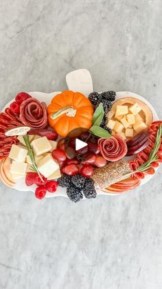 a platter filled with fruit, cheese and meats on top of a marble table