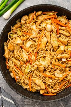 chicken lo mein in a skillet with carrots and celery on the side