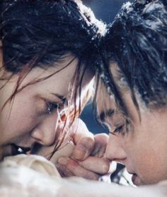 two people with wet hair are touching each other's foreheads and looking at each other