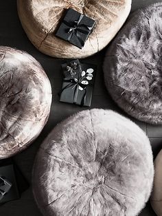 four round cushions are sitting on the floor next to presents and wrapped in black ribbon