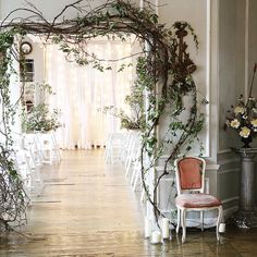 an indoor wedding ceremony with white chairs and greenery