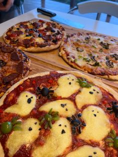 three pizzas with different toppings sitting on wooden trays next to each other