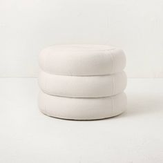 three white pillows stacked on top of each other in front of a white wall and floor