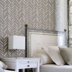 a white bed sitting under a window next to a wallpaper covered in gray arrows