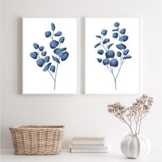 two blue flowers are displayed on the wall next to a wicker basket and vase