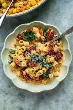 two bowls filled with pasta and vegetables on top of a marble table next to a bowl of broccoli