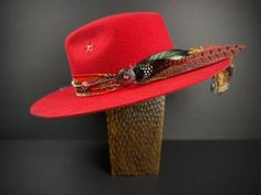 The Memphis Fedora This stunning red fedora is inspired by the sounds and sights of memphis. Featuring a gorgeous paisley silk fabric hat band, topped with our faux suede band with red coral details. Featuring our distinctive handstitched star. Feathers include a combination of both rooster asnd pheasant. Available in Large 59cm only. *Please note that this is a 'stiff' style hat* Western Style Red Hat, Red Fedora With Curved Brim, Red Western Hat Bands For Rodeo, Red Western Style Hat Band For Rodeo, Adjustable Red Fedora Hat Band, Red Adjustable Fedora With Curved Brim, Red Fedora With Flat Brim, Red Flat Brim Hat For Rodeo, Red Adjustable Flat Brim Fedora