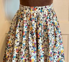 "This is a skirt from the late 50's. It is a very tiny, petite size.  Theoretically one who sews could replace the waist band and stretch out the pleats to enlarge .  The skirt is a cotton fabric, I think it is a cotton sateen, as it has one side with a smoother texture. It has a pattern of flowers in black, yellow, orange,blue, and heliotrope on a cream background. Very pretty! Skirt closes with a metal zipper and a button. Someone has moved the button over to make it smaller, and it can be mov Retro Floral Print Skirt With Relaxed Fit, Vintage Cotton Skirt With Floral Print, Vintage Floral Print Tiered Skirt, Retro Floral Print Cotton Skirt, Vintage Floral Skirt, Vintage Red Floral Print Skirt, Pretty Skirt, Klamath Falls, Floral Pencil Skirt