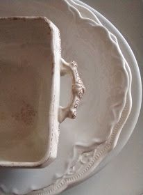 a white plate with an old looking dish on it's side and another bowl in the middle