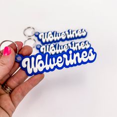 a person holding a blue and white keychain with the words valentine's written on it