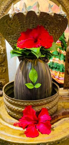 a vase with red flowers in it sitting on a table next to a flower pot