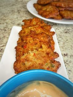 there are two plates with food on them next to a bowl of soup and some fried meat