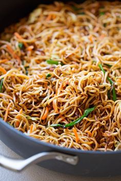 a pan filled with noodles and vegetables on top of a stove