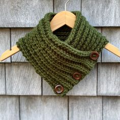 a green knitted cowl hanging from a wooden hanger