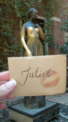 a person holding up a sign in front of a statue with the word juliet written on it