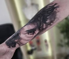 a man's arm with a black and white tattoo on it, depicting the face of jesus