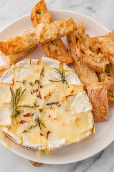 a white plate topped with cheese and crackers on top of a marble countertop