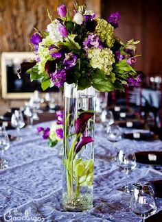 a vase filled with purple and white flowers on top of a blue table cloth covered table