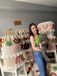 a woman holding a cat in her arms and posing for the camera with other items behind her