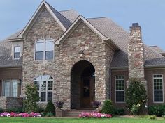 a large brick house with flowers in the front yard