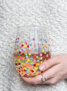 a person holding a wine glass with confetti on the bottom and inside it