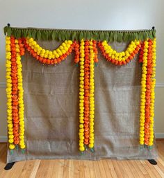 an orange, yellow and green garland is hanging on the wall next to a wooden floor