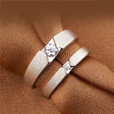 two white gold wedding rings on top of each other with a diamond in the middle