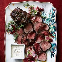 a white plate topped with meat and veggies next to a bowl of ranch dressing