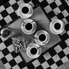 black and white photograph of coffee cups on checkered table