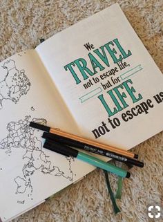 an open book on the floor with some pens and markers next to it that says we travel not to escape life, not to escape us