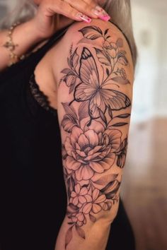 a woman with a butterfly and flowers tattoo on her arm