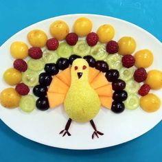 a white plate topped with fruit and a turkey made out of grapes, raspberries