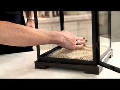 a person reaching into a glass case with sand in it