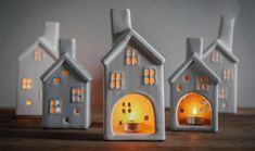 three small houses with candles in them sitting on a wooden table next to each other