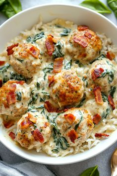 a white bowl filled with meatballs covered in cheese and spinach