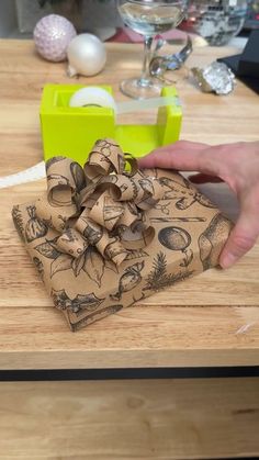 a person holding a bow on top of a wooden table next to an egg carton