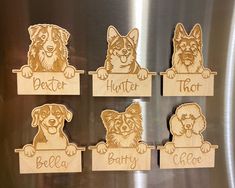 four wooden cutouts of dogs with name tags on the front of a stainless steel refrigerator