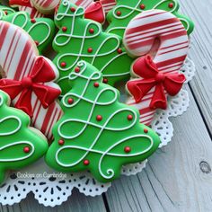 christmas cookies decorated with green and red icing on a white doily platter