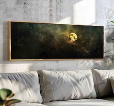 a living room with a white couch and a painting on the wall above it that has a full moon in the sky