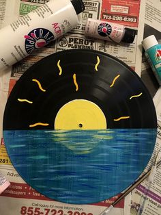 a record with the sun painted on it next to some markers and paint tubes,