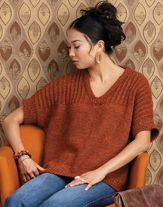 a woman sitting on an orange chair in front of a wall