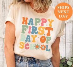 a woman wearing a t - shirt that says happy first day of school on it