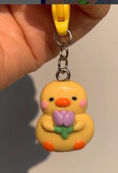 a yellow rubber ducky keychain with a pink flower in it's mouth