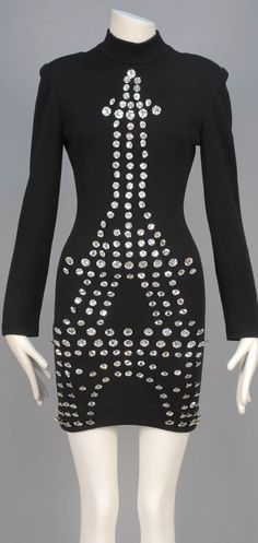 Dress for the Eiffel Tower's centennial, Patrick Kelly, 1989. Long-sleeved black wool knit sheath with mock turtleneck and padded shoulder decorated with oversized Eiffel Tower comprising rhinestone buttons in varied sizes. Whitaker Auctions Eiffel Tower Dress, Fashion Timeline, Patrick Kelly, Philadelphia Museum Of Art, 1990s Fashion, Mock Turtleneck, Wool Knit, Black Wool, The Professional