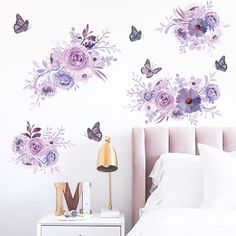 a white bed sitting next to a wall with purple flowers and butterflies painted on it