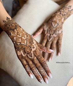 a woman's hand with henna tattoos on it, and her hands showing the intricate