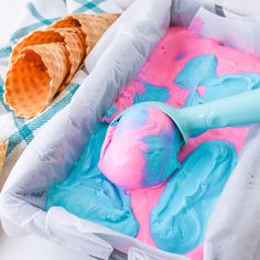 an ice cream sundae with blue, pink and orange icing in a pan