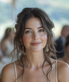 a close up of a person wearing a dress and smiling at the camera with other people in the background