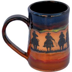 a coffee mug with the silhouette of cowboys riding horses on an orange and blue background